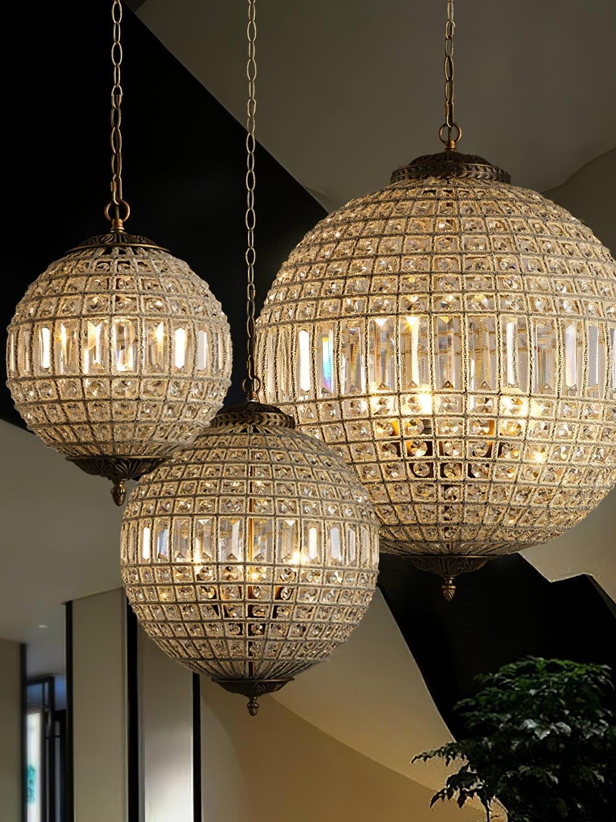 Three glowing crystal globe fixtures at different heights with rectangular middle bands and ornate metal details