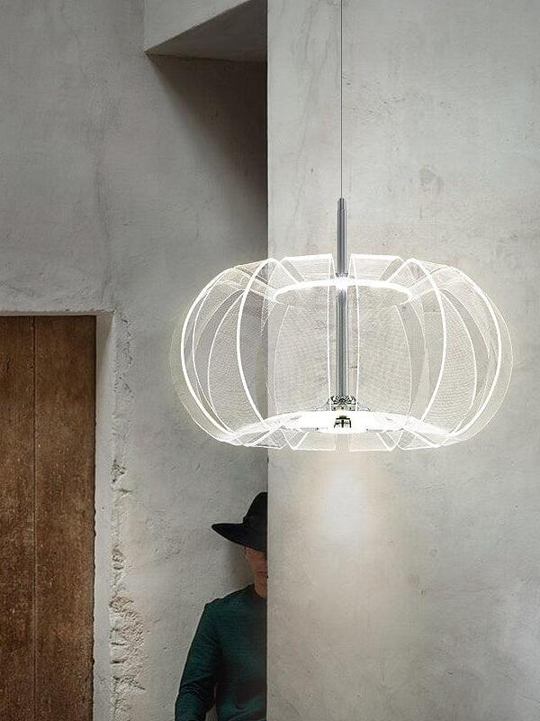 Illuminated clear acrylic cage pendant in a plaster room beside a wooden door