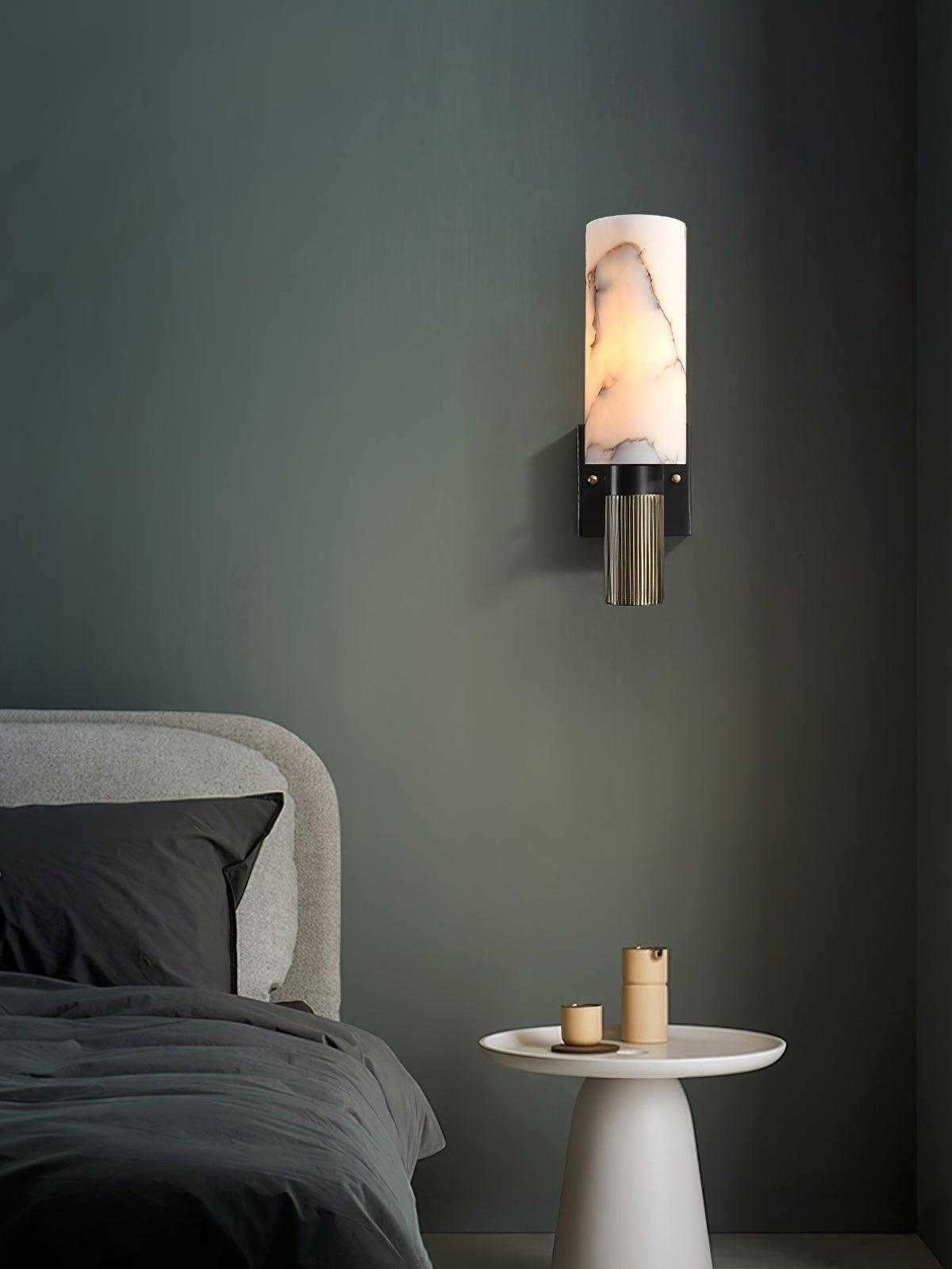 Small marble wall light beside a bed on green wall
