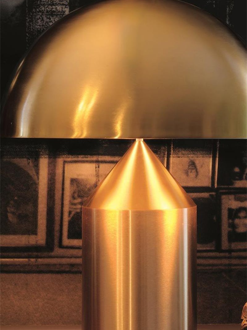 Close view of a gold-tone dome shade above the cone-topped cylindrical base in warm light