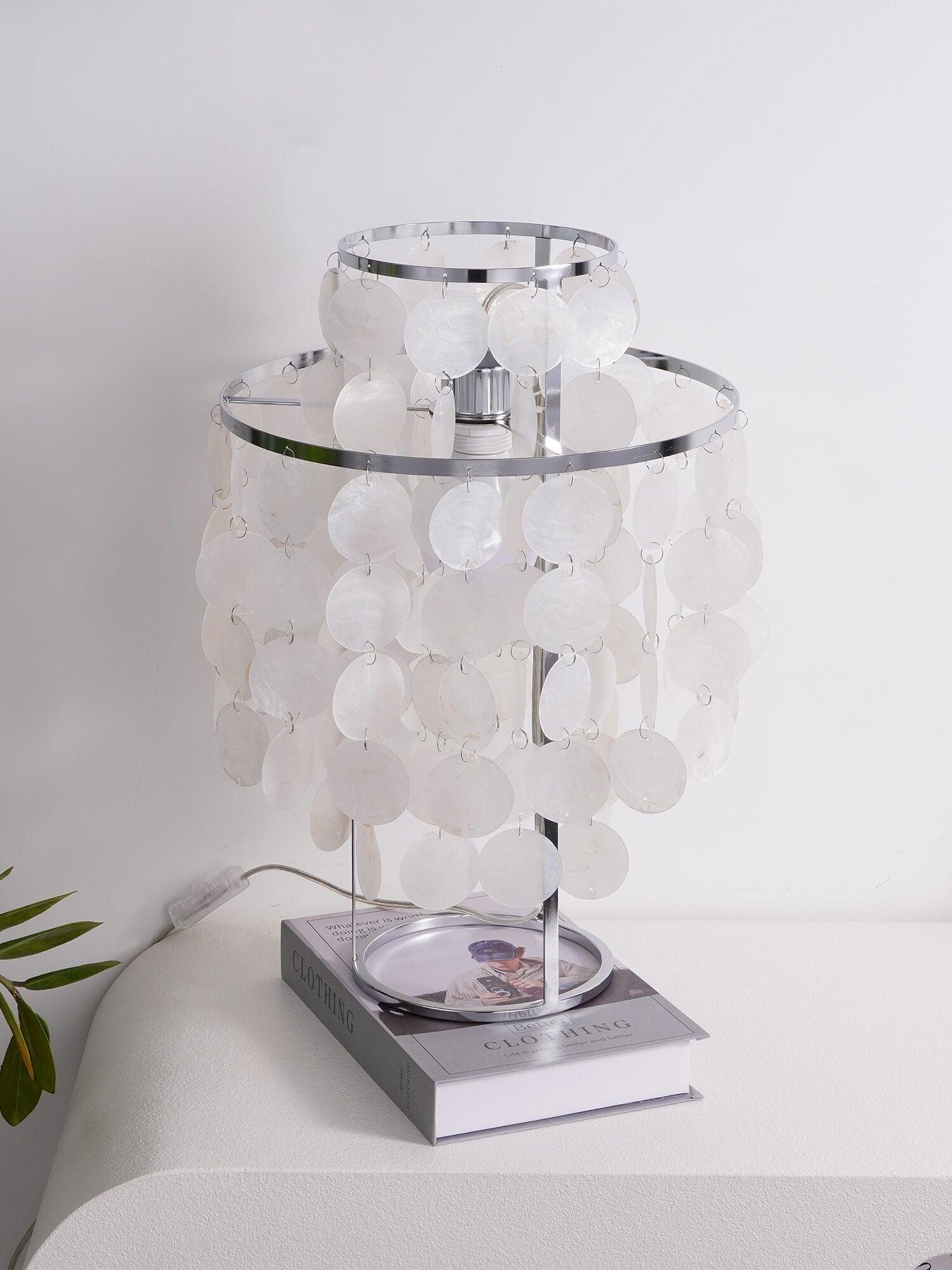 Unlit shell table lamp with round base resting on book