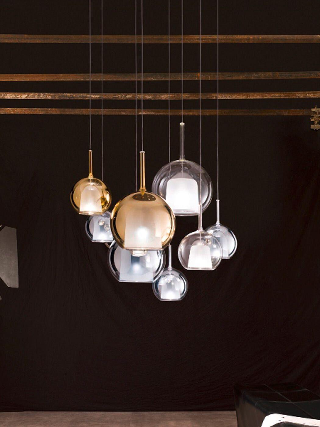 Separate globe pendants hanging at varied heights beneath a slatted ceiling in a dark room