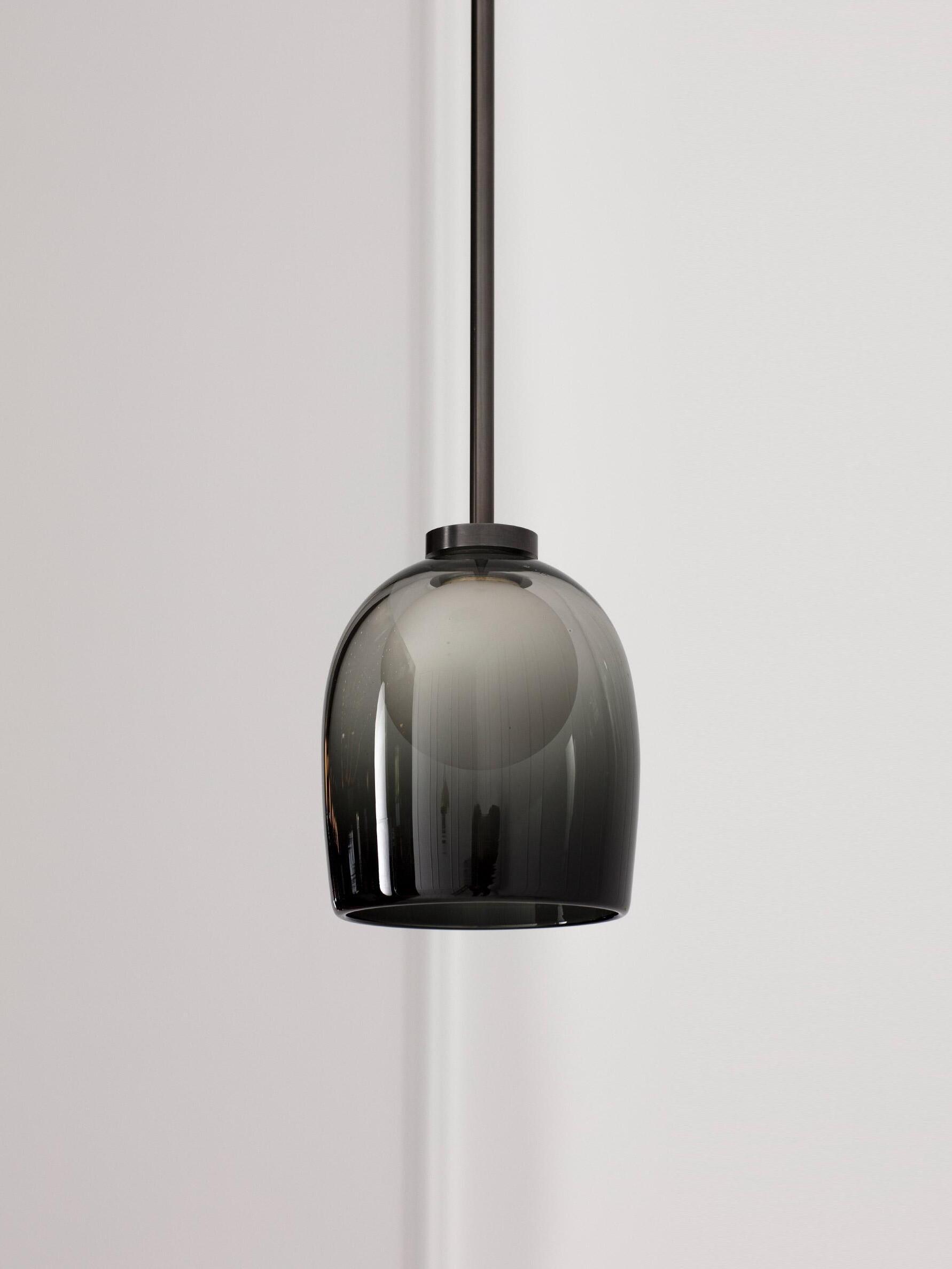 Unlit gradient-black Crux bell shade hanging from a dark suspension cord