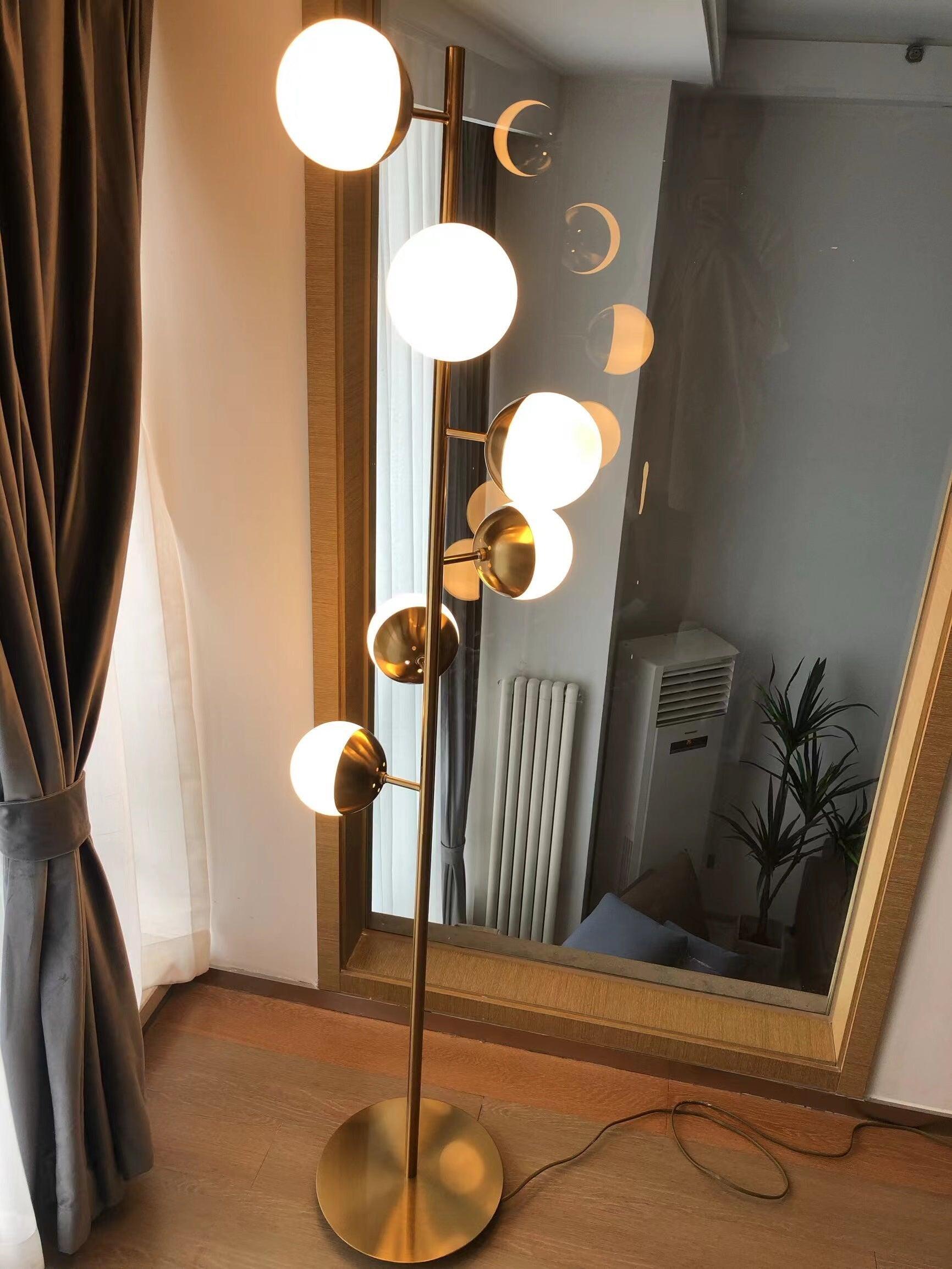 Tall gold lamp beside mirror with cord at base