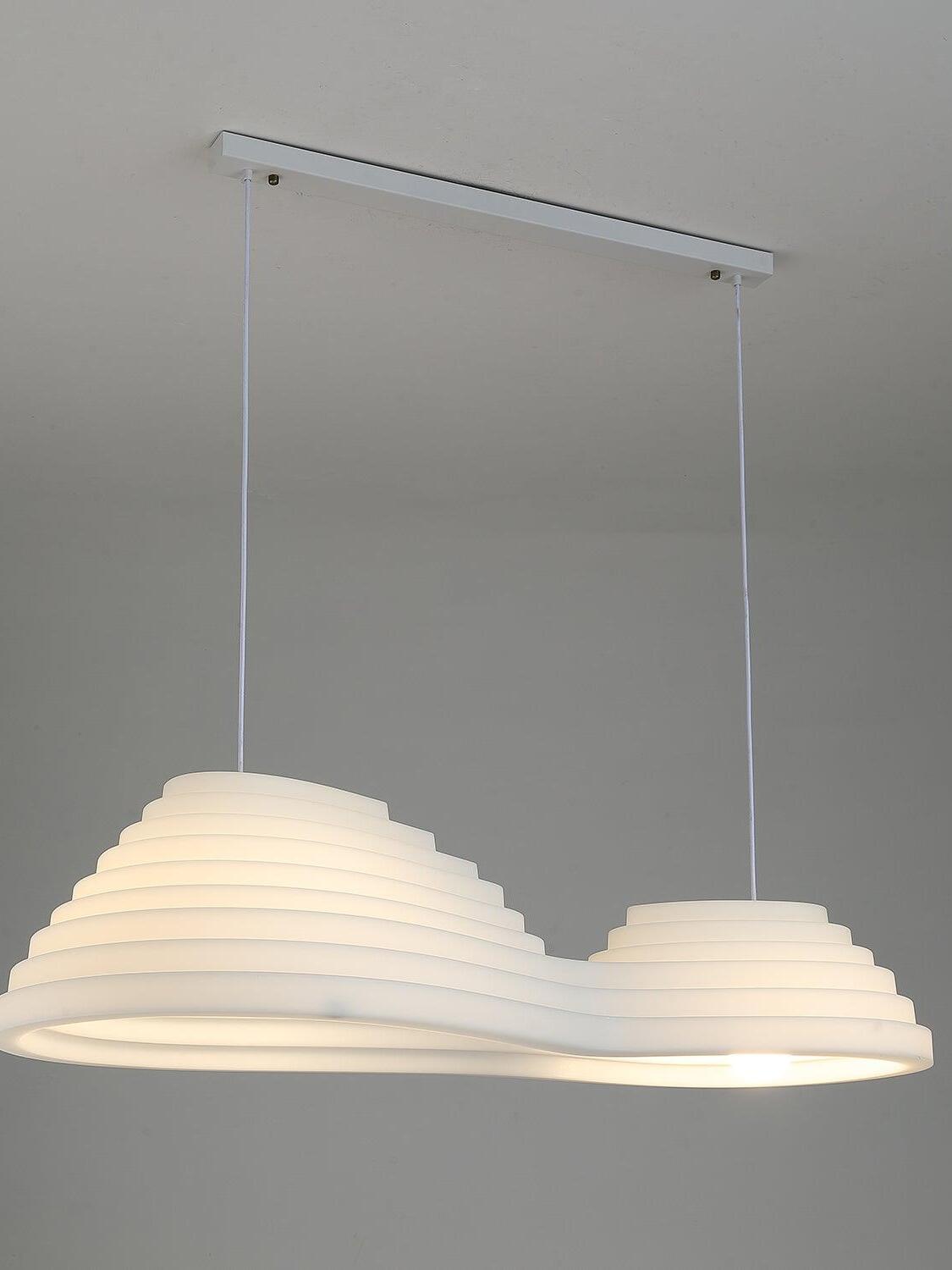 Elongated white pendant lit with a warm-looking glow, suspended from a rectangular ceiling canopy.