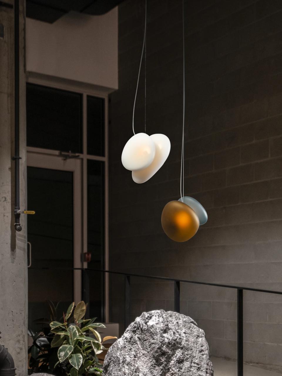 White and amber-grey pebble pendants against a dark wall