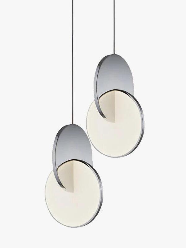 Two chrome disc pendant lights on separate cords at different drops against white
