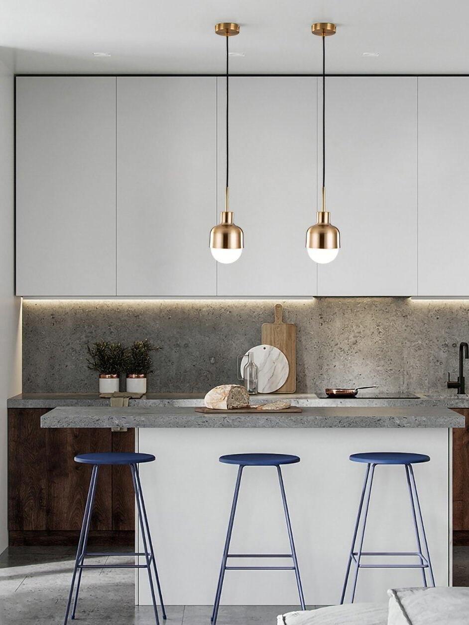 Two separate Niku pendants above a kitchen island with gray cabinets and blue stools