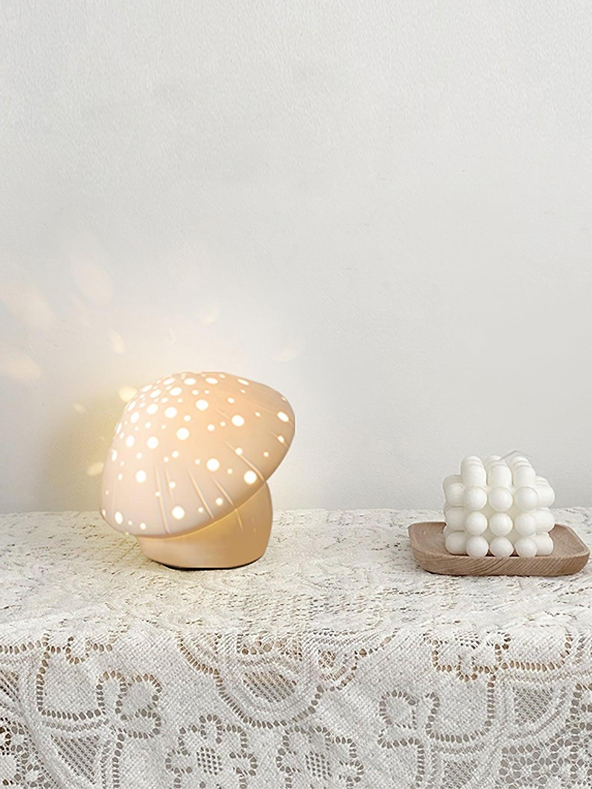 Warm-looking Fungo lamp on a lace-covered surface beside a white decorative candle