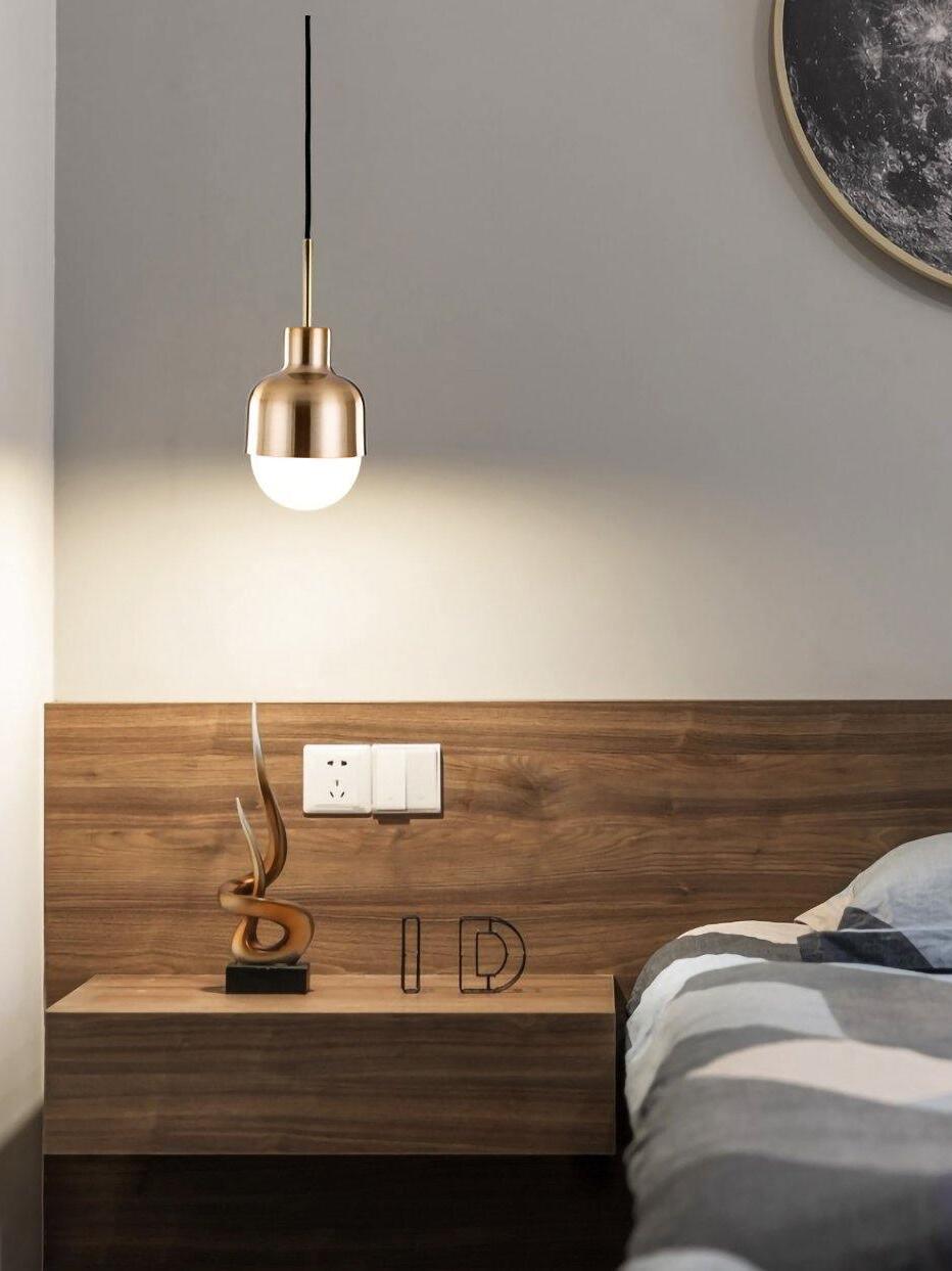 Single Niku pendant lit above a wooden bedside shelf with an abstract ornament beside a bed