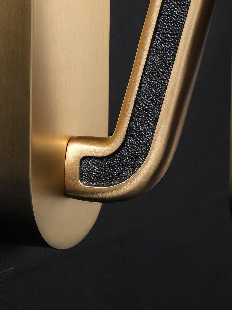 Macro view of a gold-tone curved arm with dark textured inset beside the rounded wall backplate