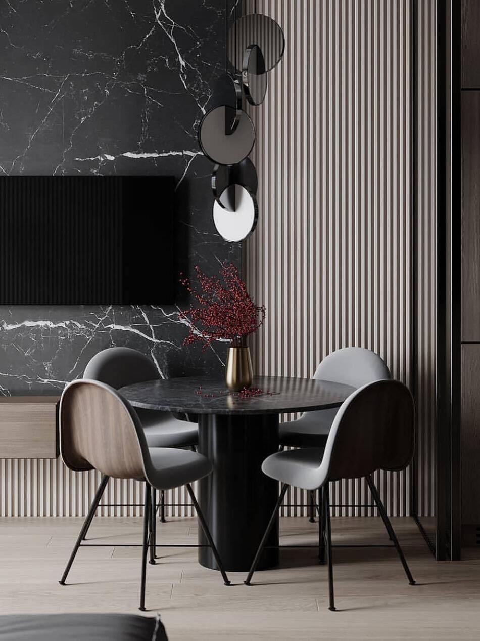 Reflective disc pendants above a round dining table with a vase, chairs and dark fluted wall