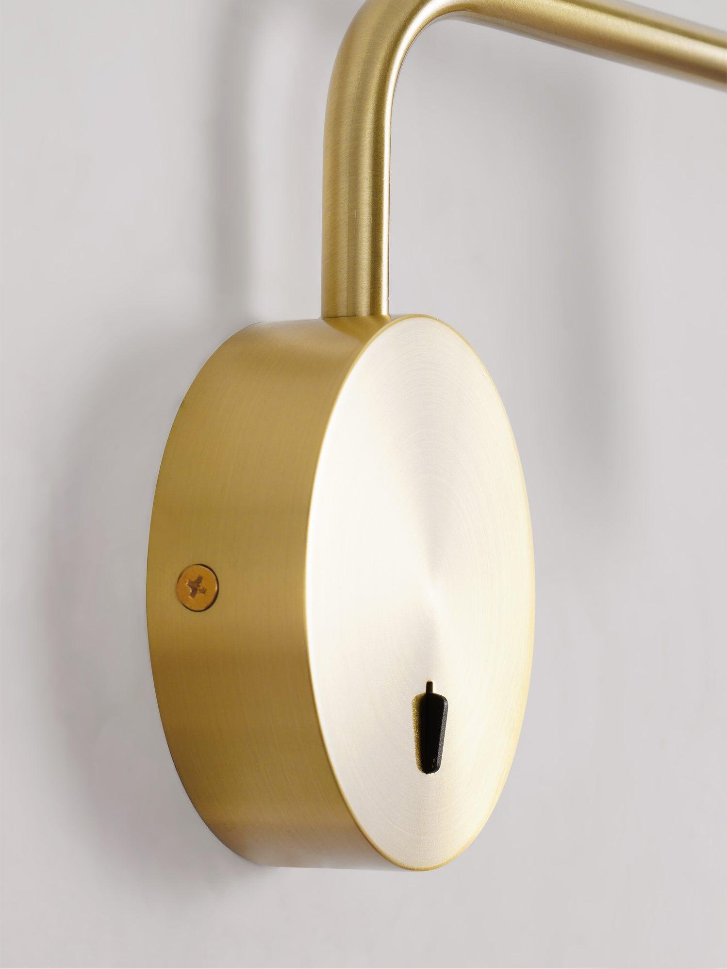 Round gold-coloured wall plate with small black switch