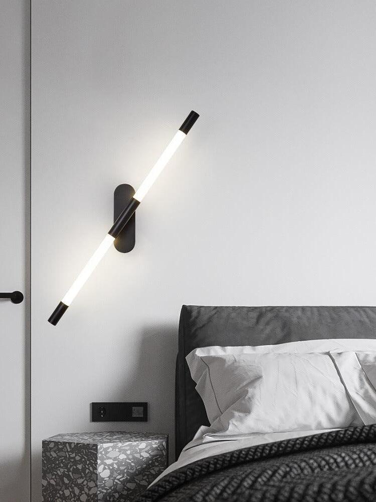 Angled black Agnes wall light above a grey upholstered bed