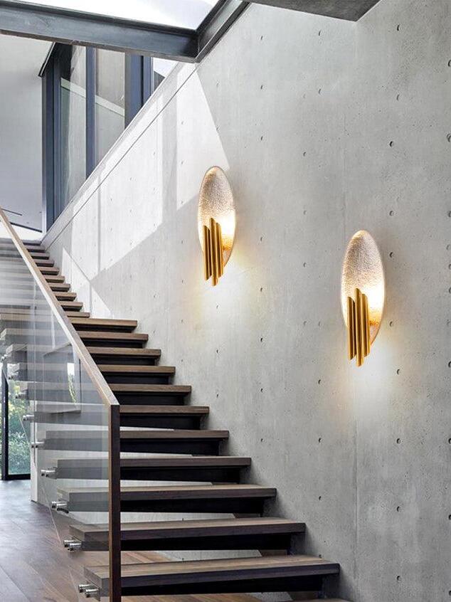 Two silver-tone oval wall lights along indoor concrete stair wall