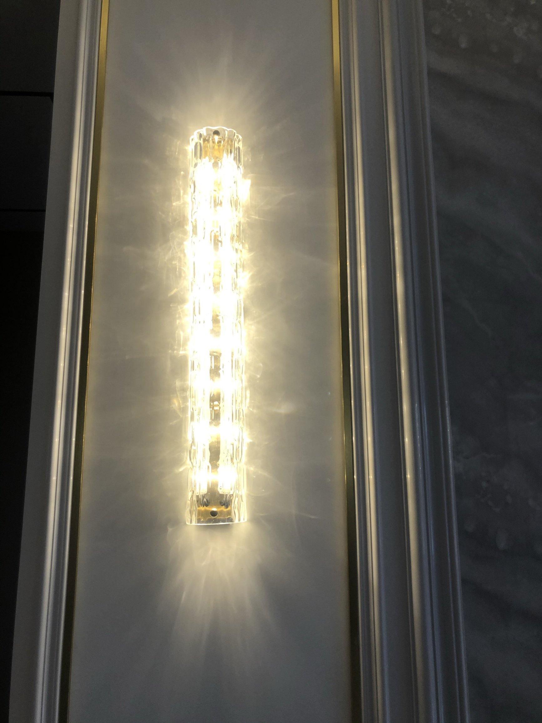 Warm-lit glass bar beside gold-edged dark wall panels
