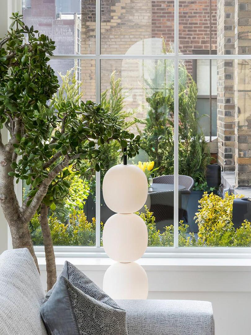 Partial white globe lamp beside a window and plant