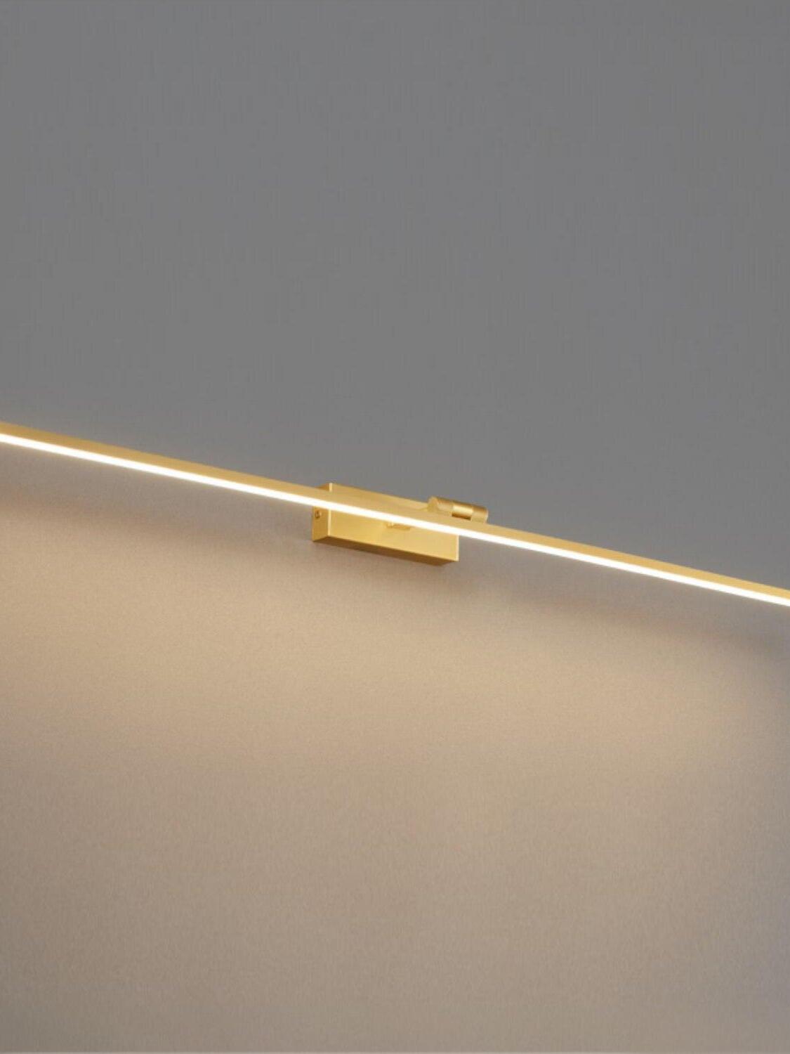 Illuminated polished-brass linear wall light with rectangular wallplate against grey wall