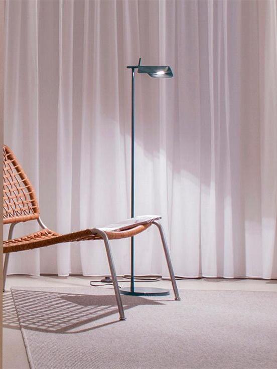 Blue-grey floor lamp near a lounge chair and curtains