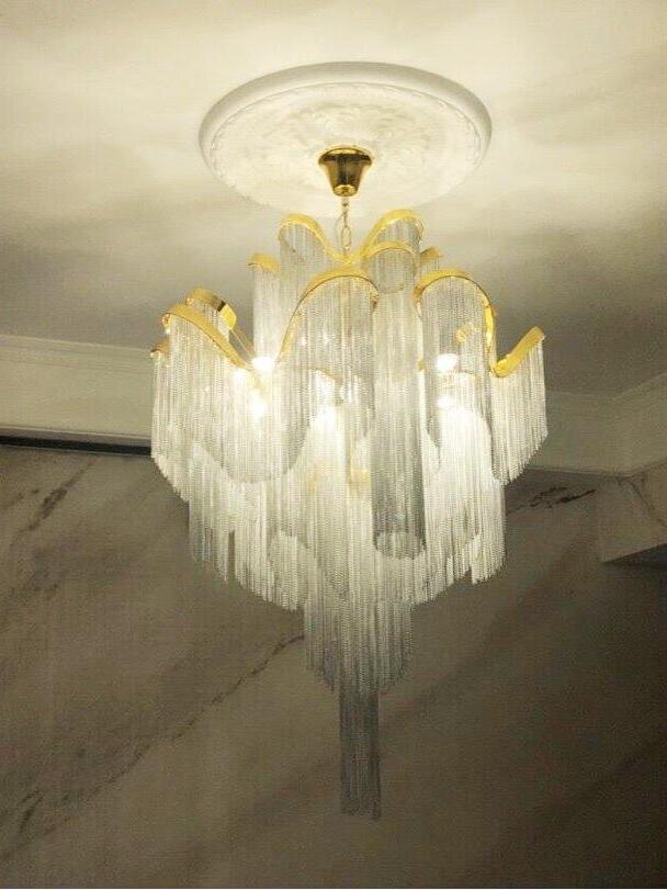 Gold-edged chain chandelier glowing above a table