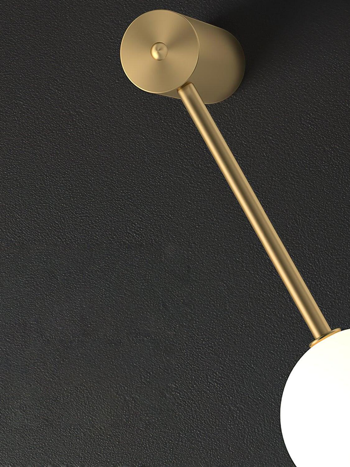 Close view of cylindrical gold-colour wall fitting, round face, vertical rod and a cropped white globe