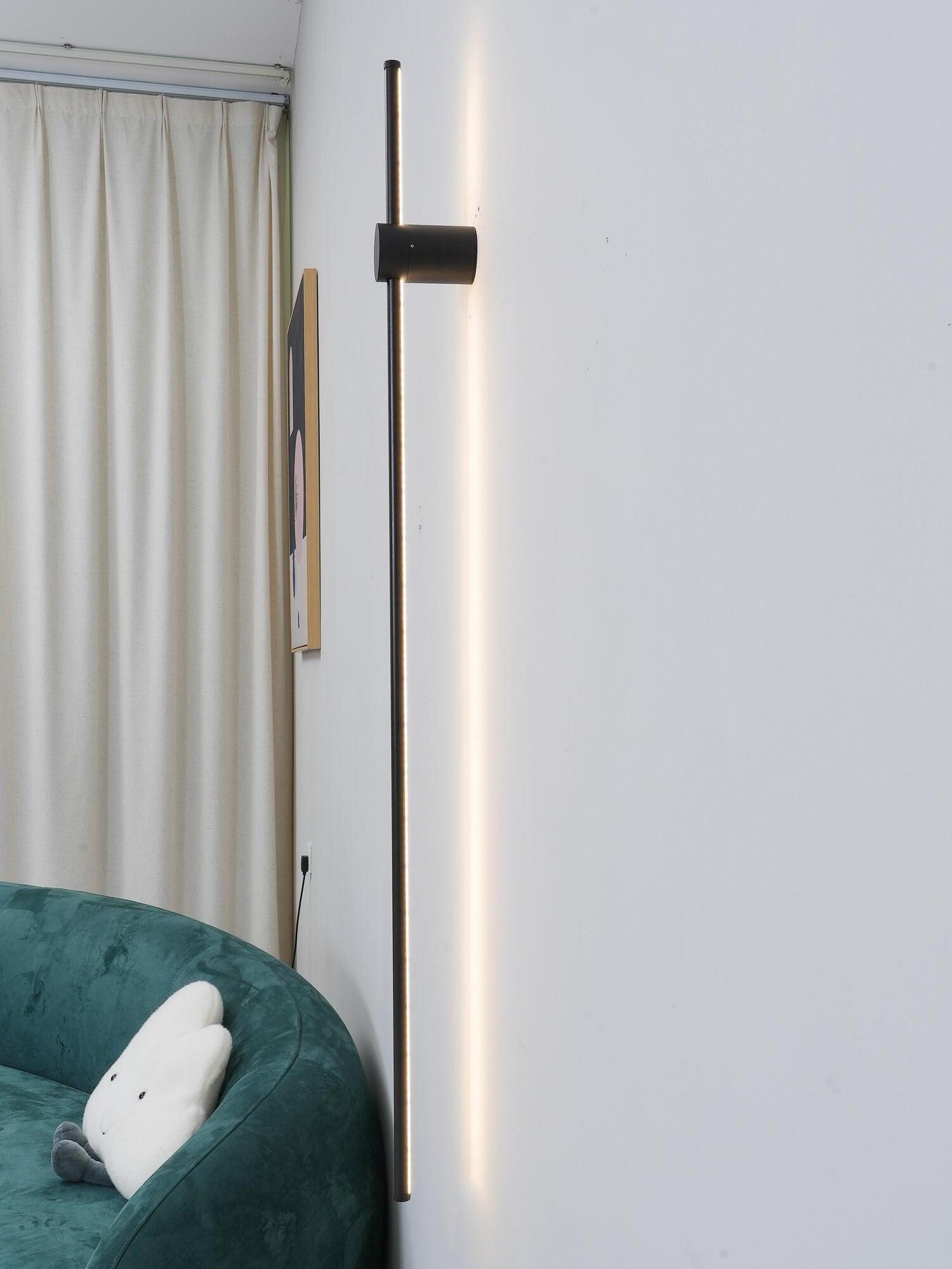 Vertical linear light near curtains and a green sofa