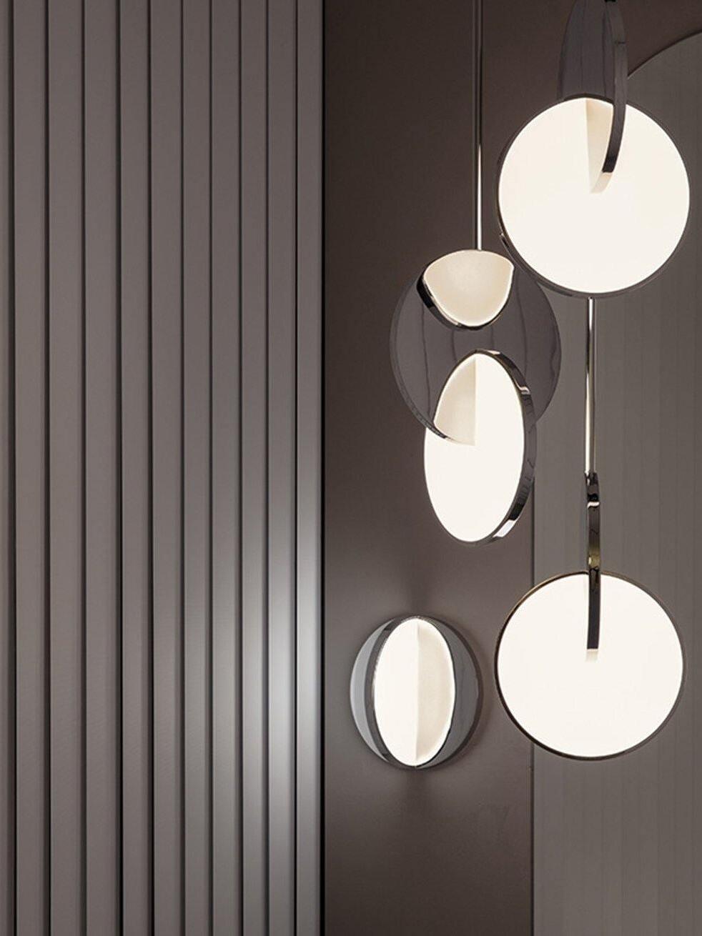 Chrome disc pendants and a separate circular wall lamp against a dark panelled wall