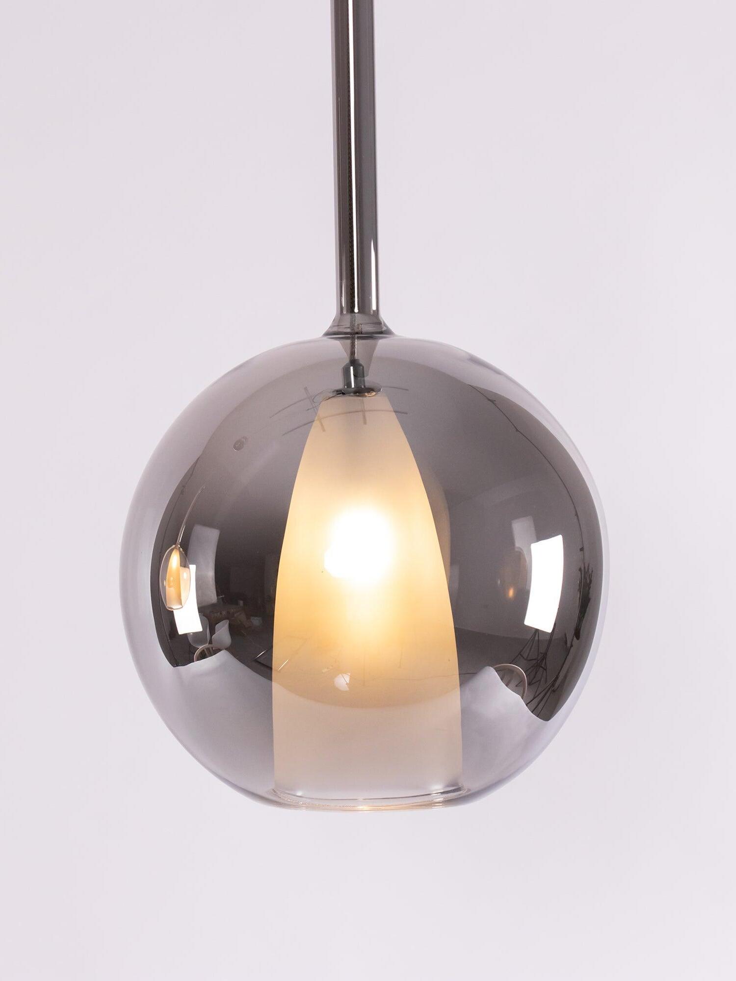 Reflective smoked-looking glass globe with an illuminated white inner shade on white