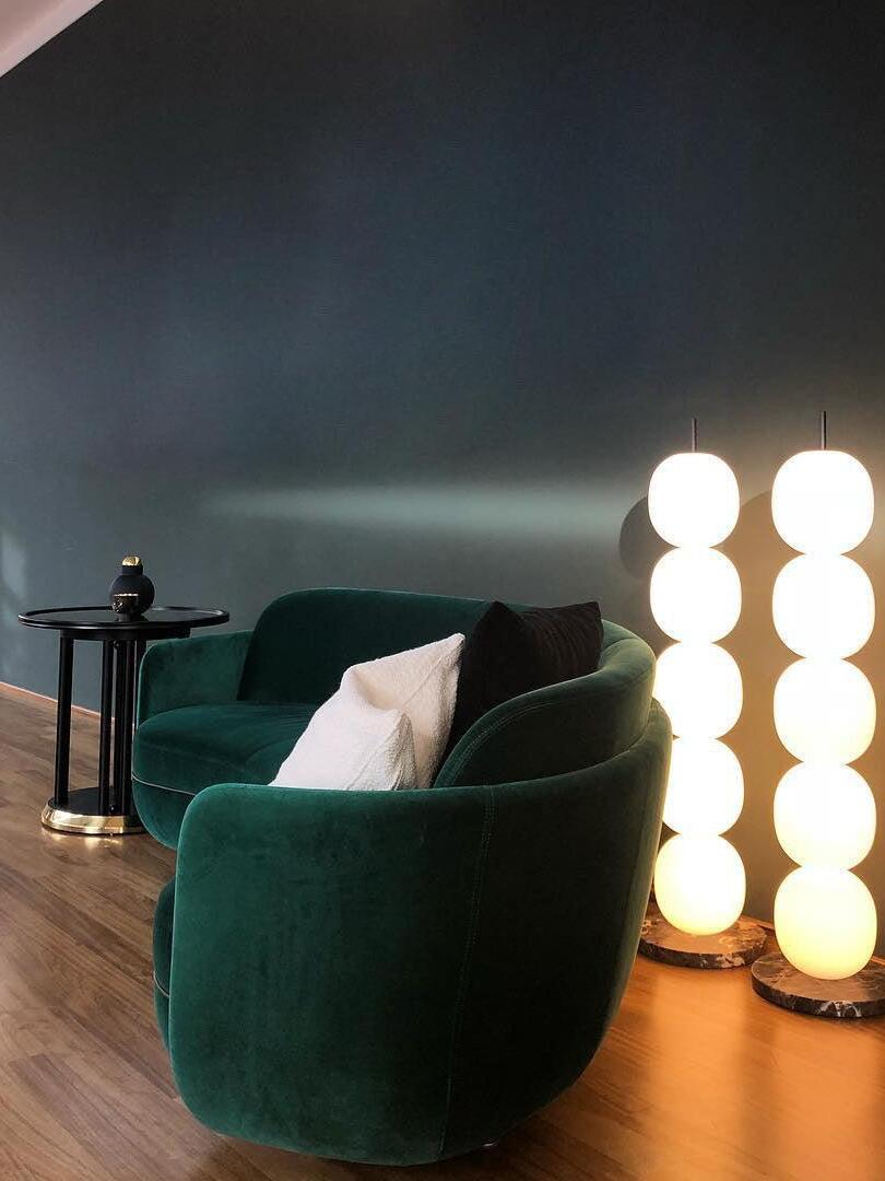 Two illuminated globe columns behind green armchair