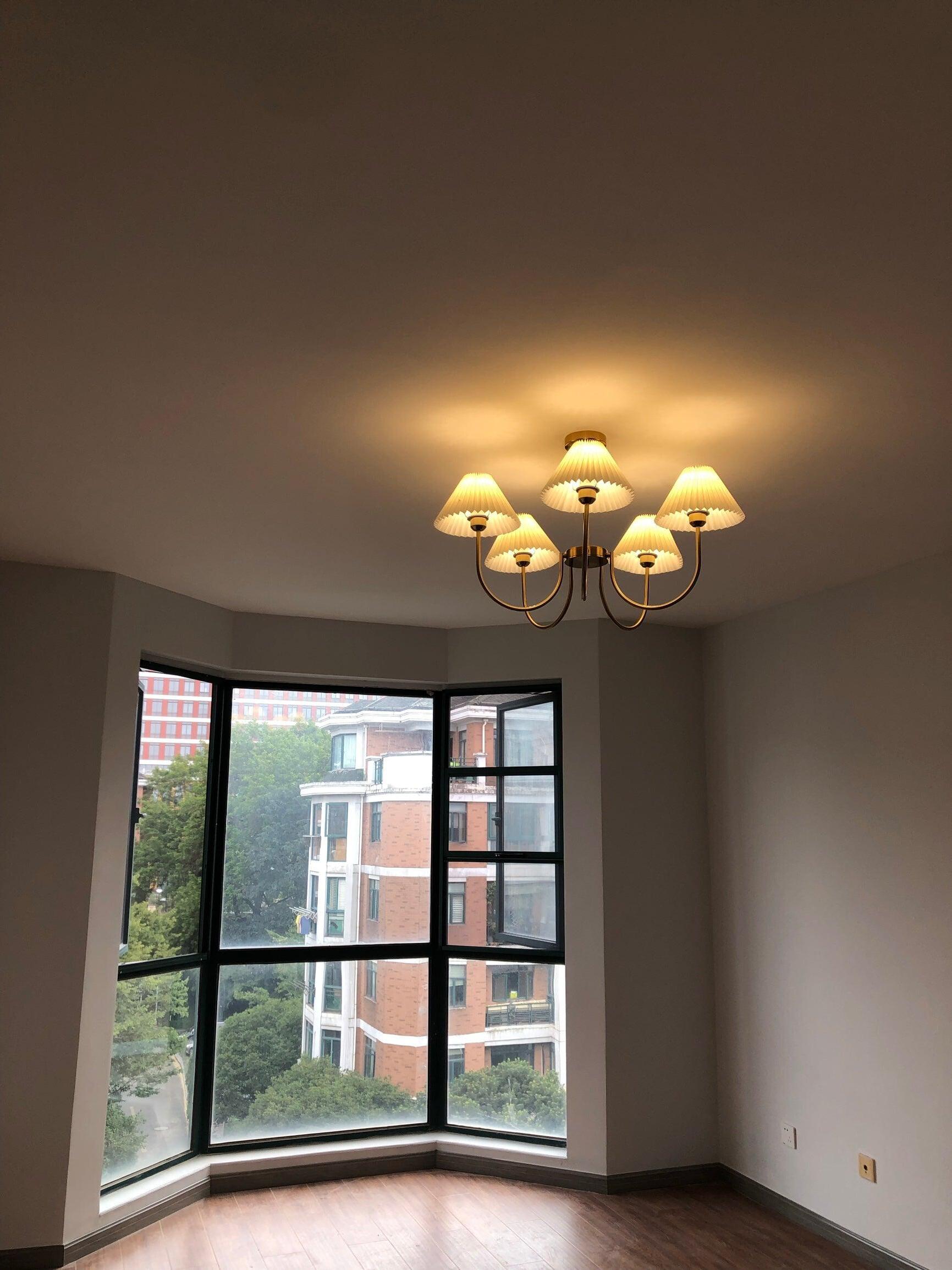 Warm-looking chandelier in an empty room beside corner windows