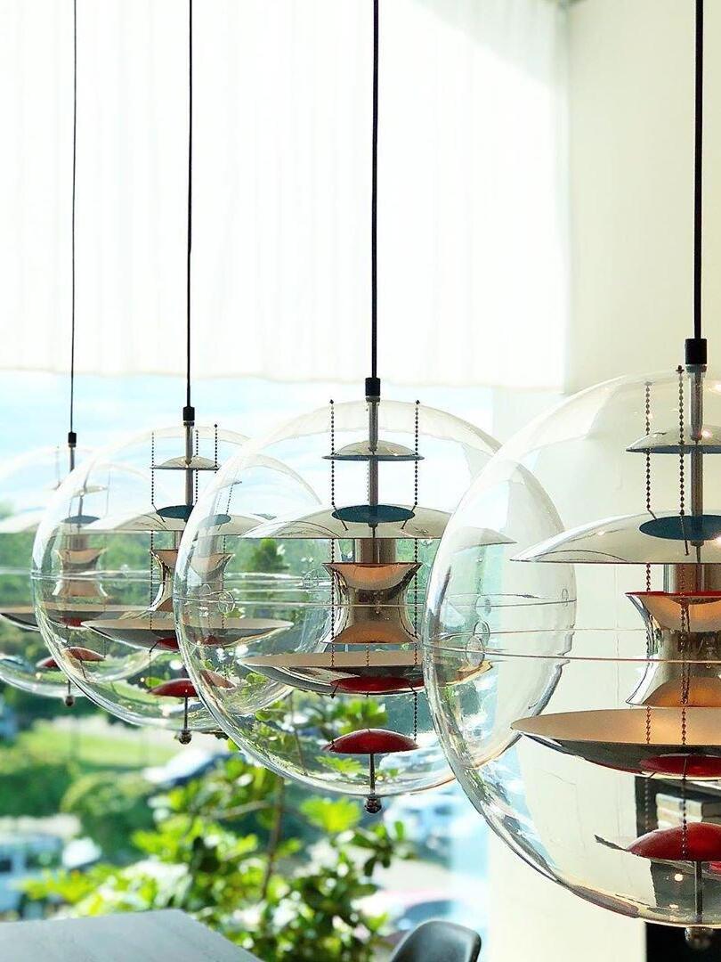 Four separate clear globe pendants with gold-tone internal parts arranged beside a bright window