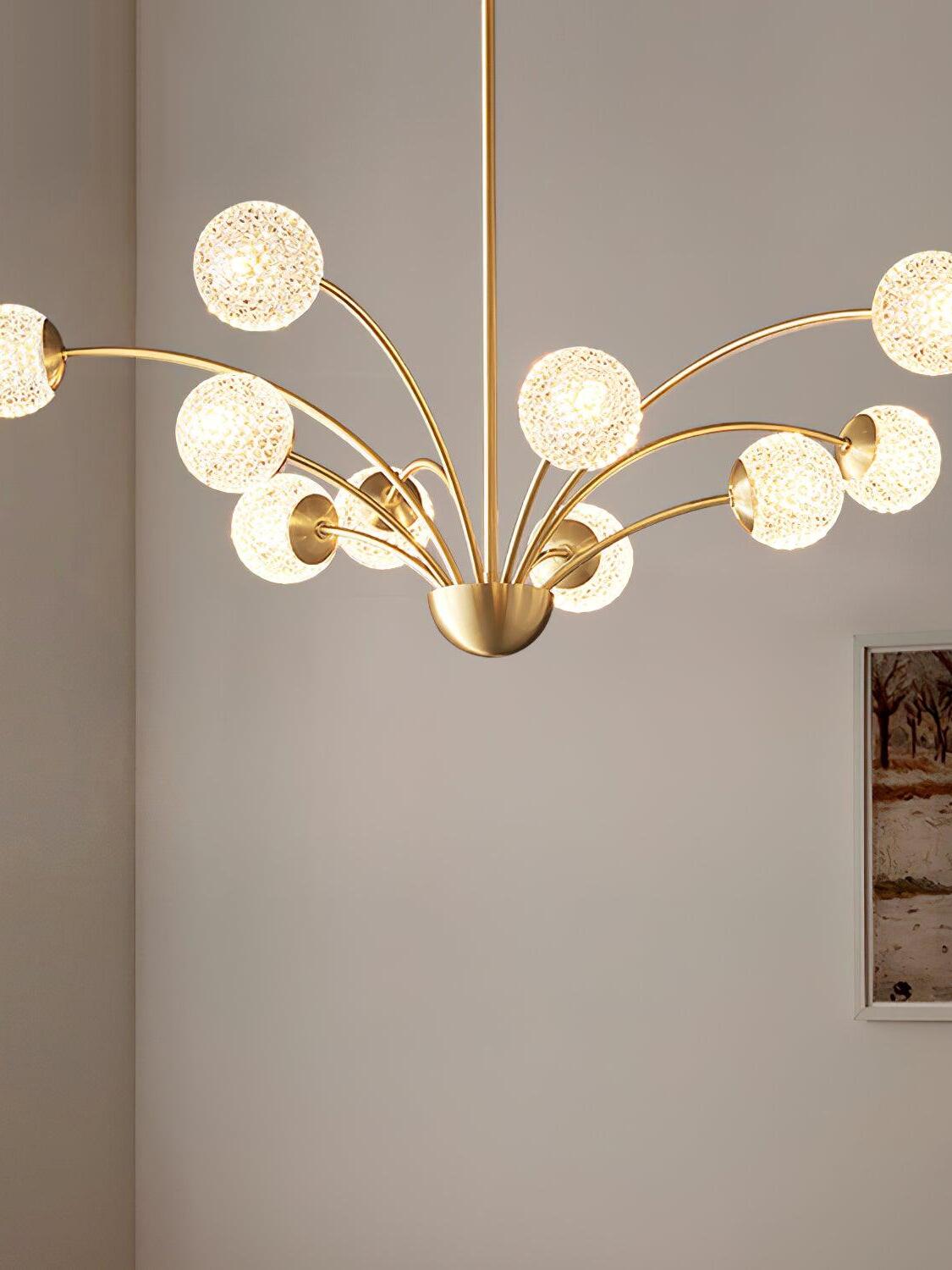 Close cropped view of glowing textured globes and curved brass-tone arms against a pale wall
