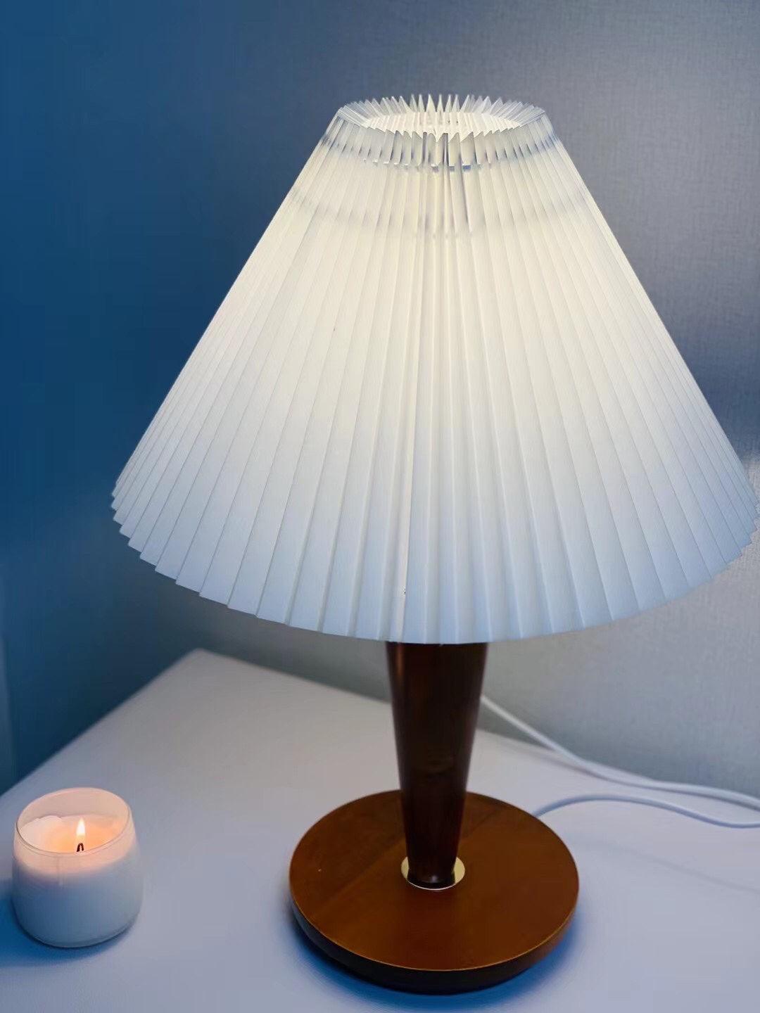 Close view of white pleated shade over brown lamp stem