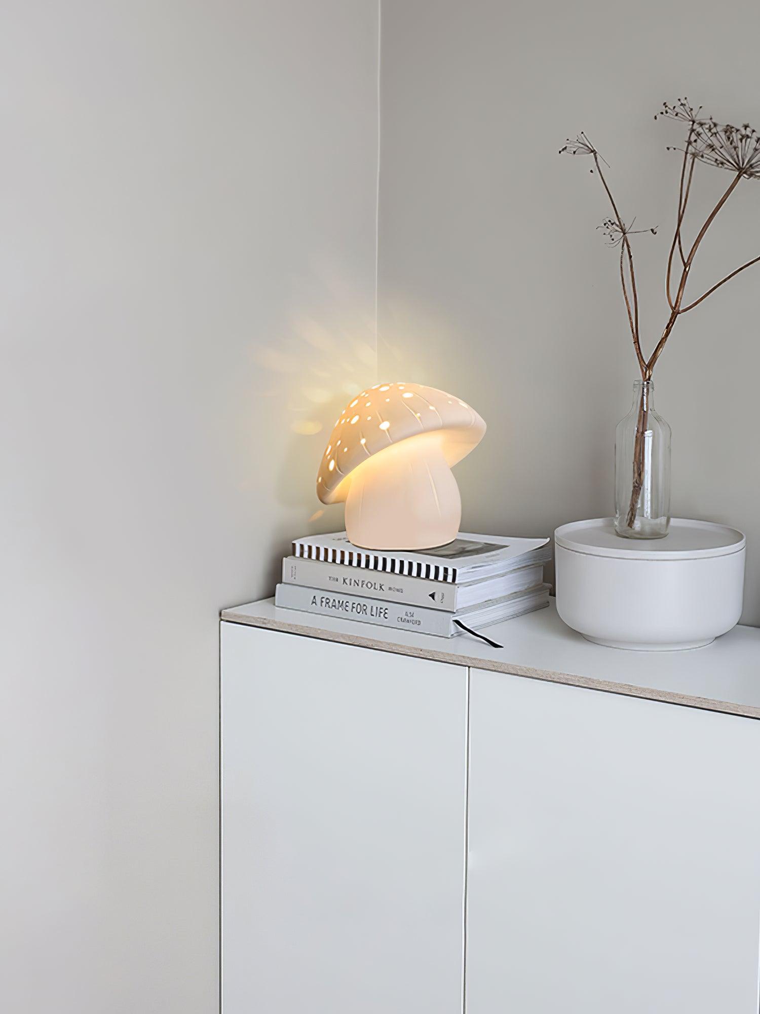 Fungo lamp on stacked books above a white cabinet beside a vase with branches