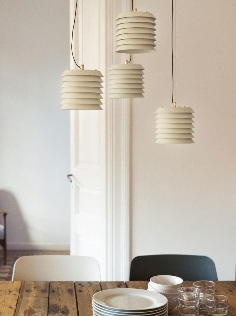 Four white layered pendants above wood dining table with plates and glasses