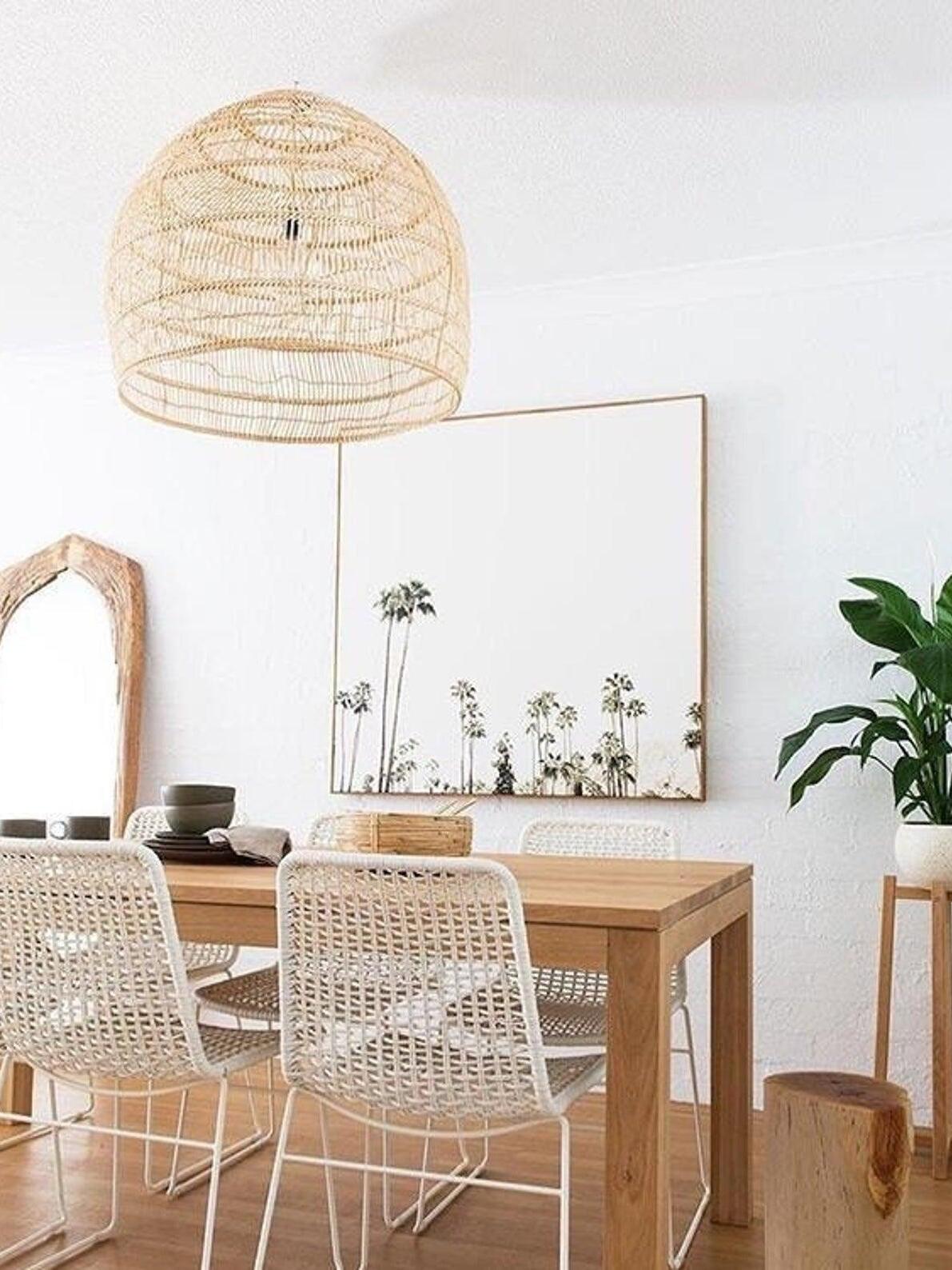 Natural basket pendant above a wooden dining table with a large wall mirror