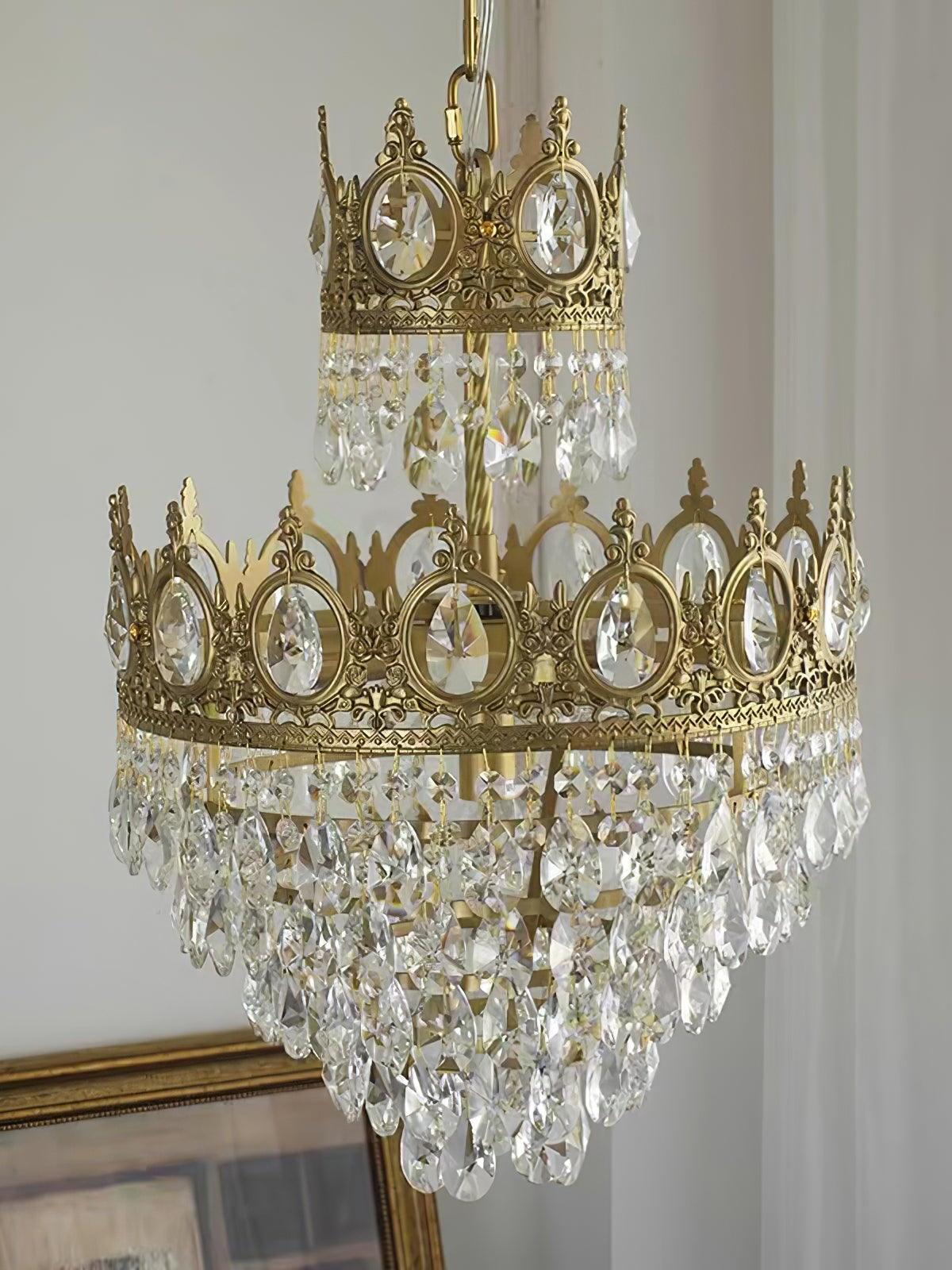 Unlit crystal chandelier by a window, with ornate circular crown inserts and a tapering lower drop cluster