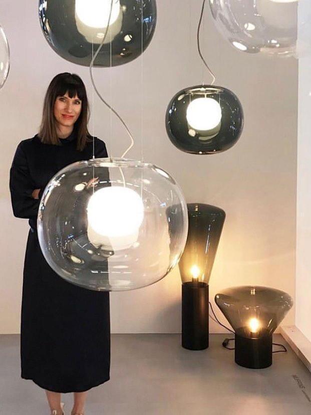 Person beside a display of illuminated globe pendants