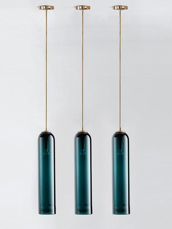 Three blue-green glass tube pendants side by side at equal heights, each with a separate gold-toned rod and ceiling canopy