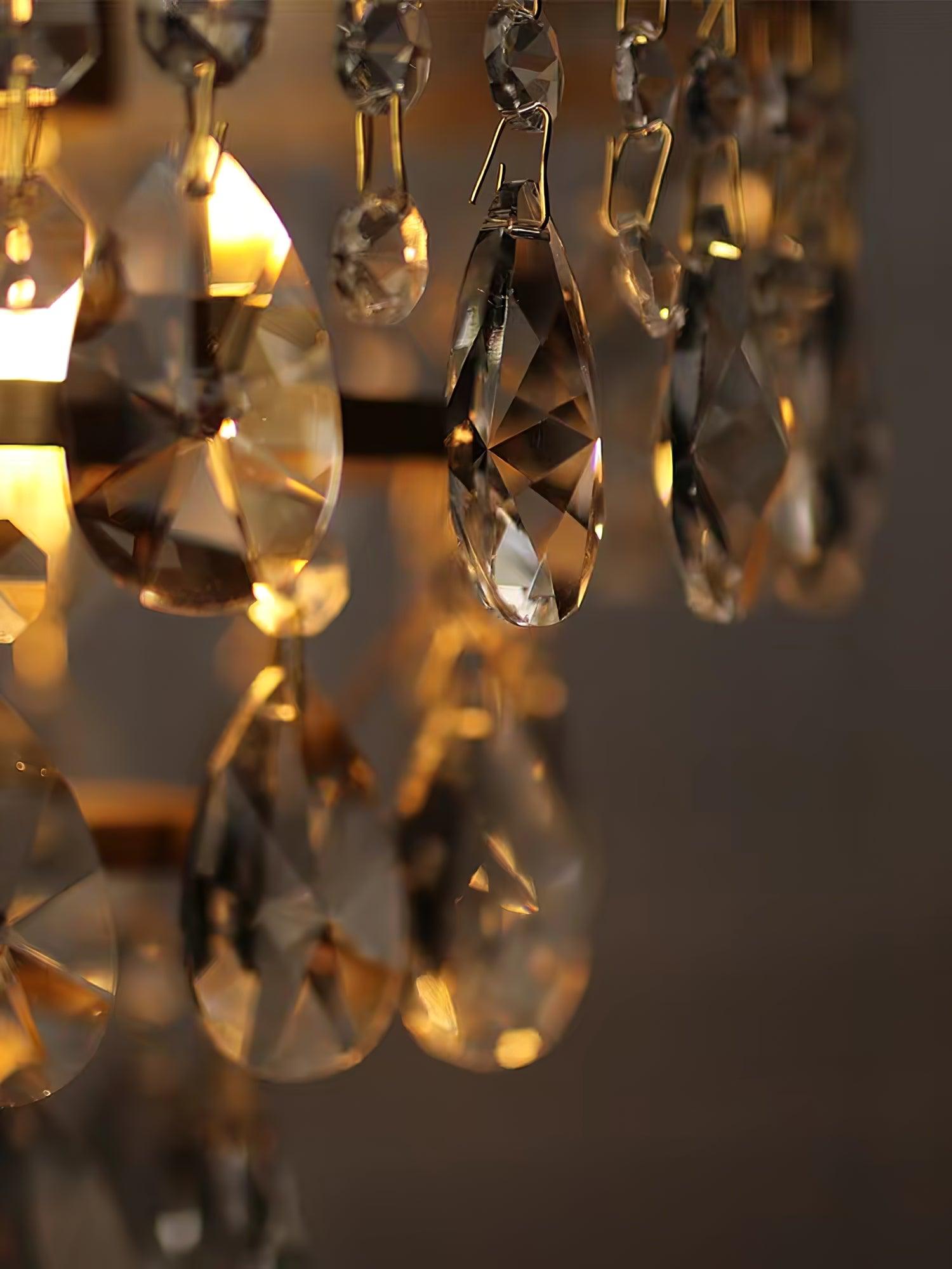 Close-up of hanging faceted crystal drops and metal links with warm light behind them.