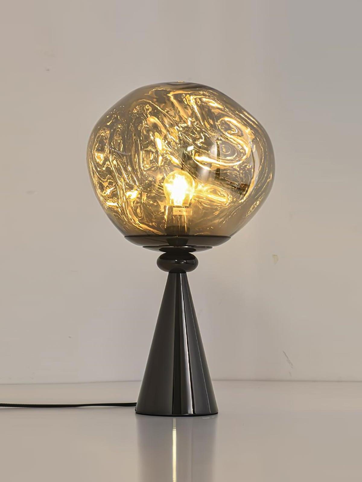 Glowing irregular globe on a black cone base with a cord resting on a white table