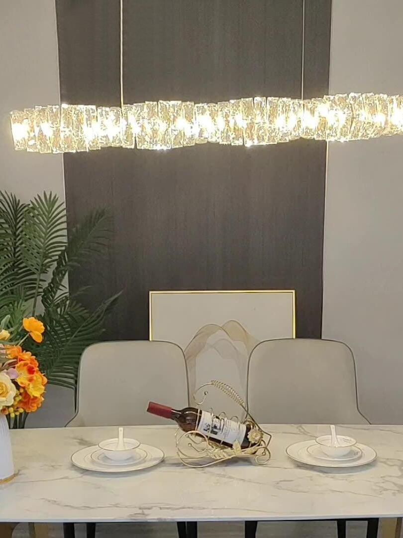 Warm-looking crystal pendant above a marble dining table set with plates and a wine bottle