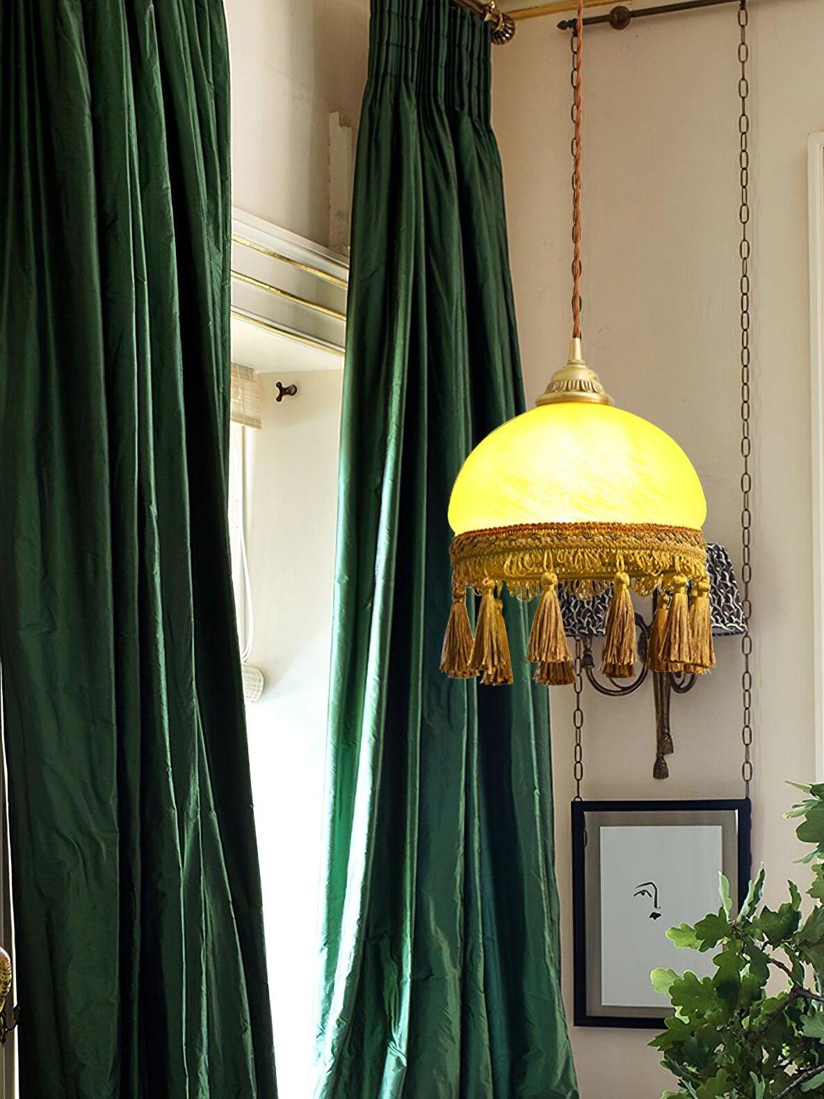 Yellow dome tassel pendant beside green velvet curtains