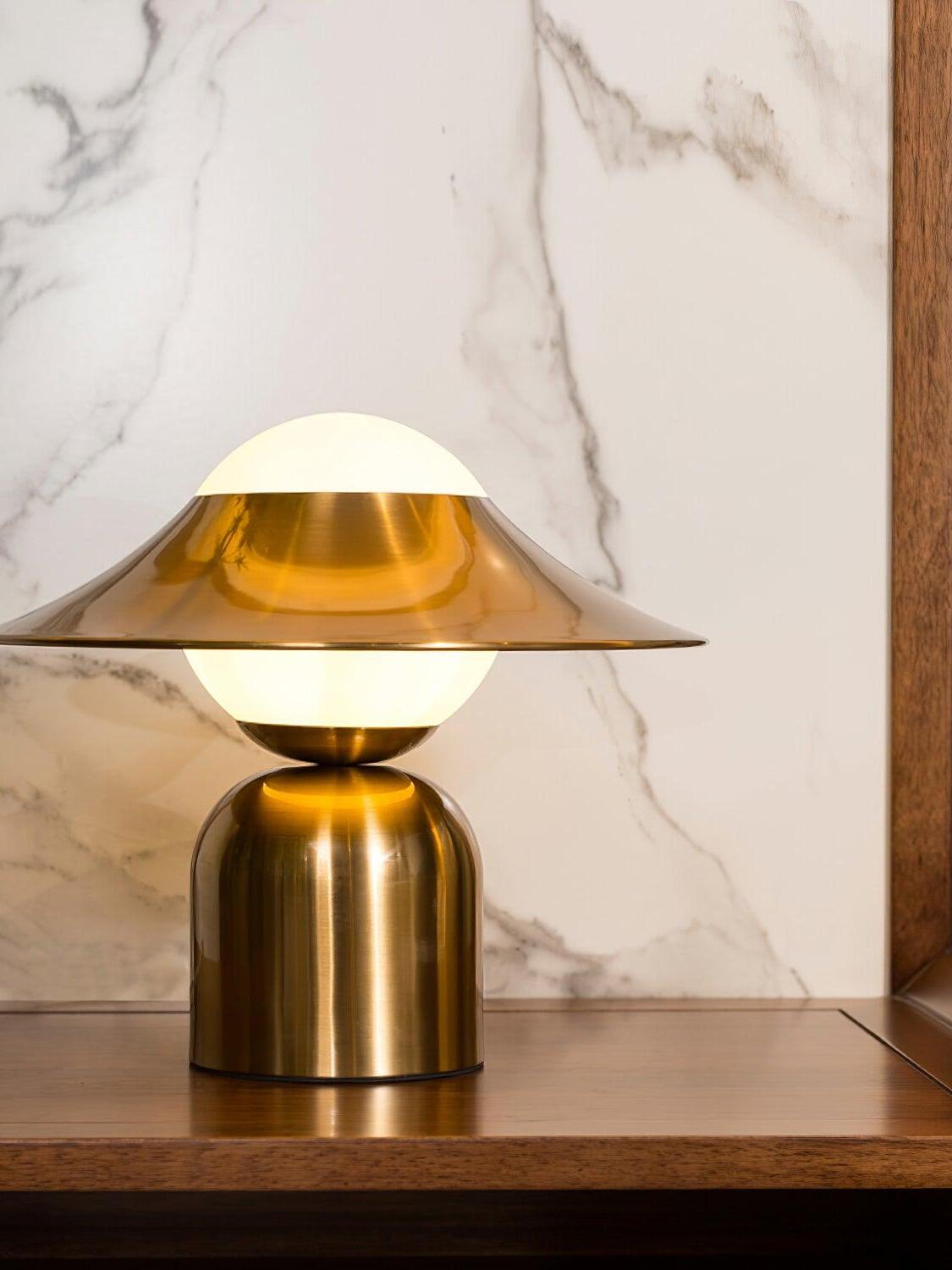 Gold disc table lamp against marble-patterned wall