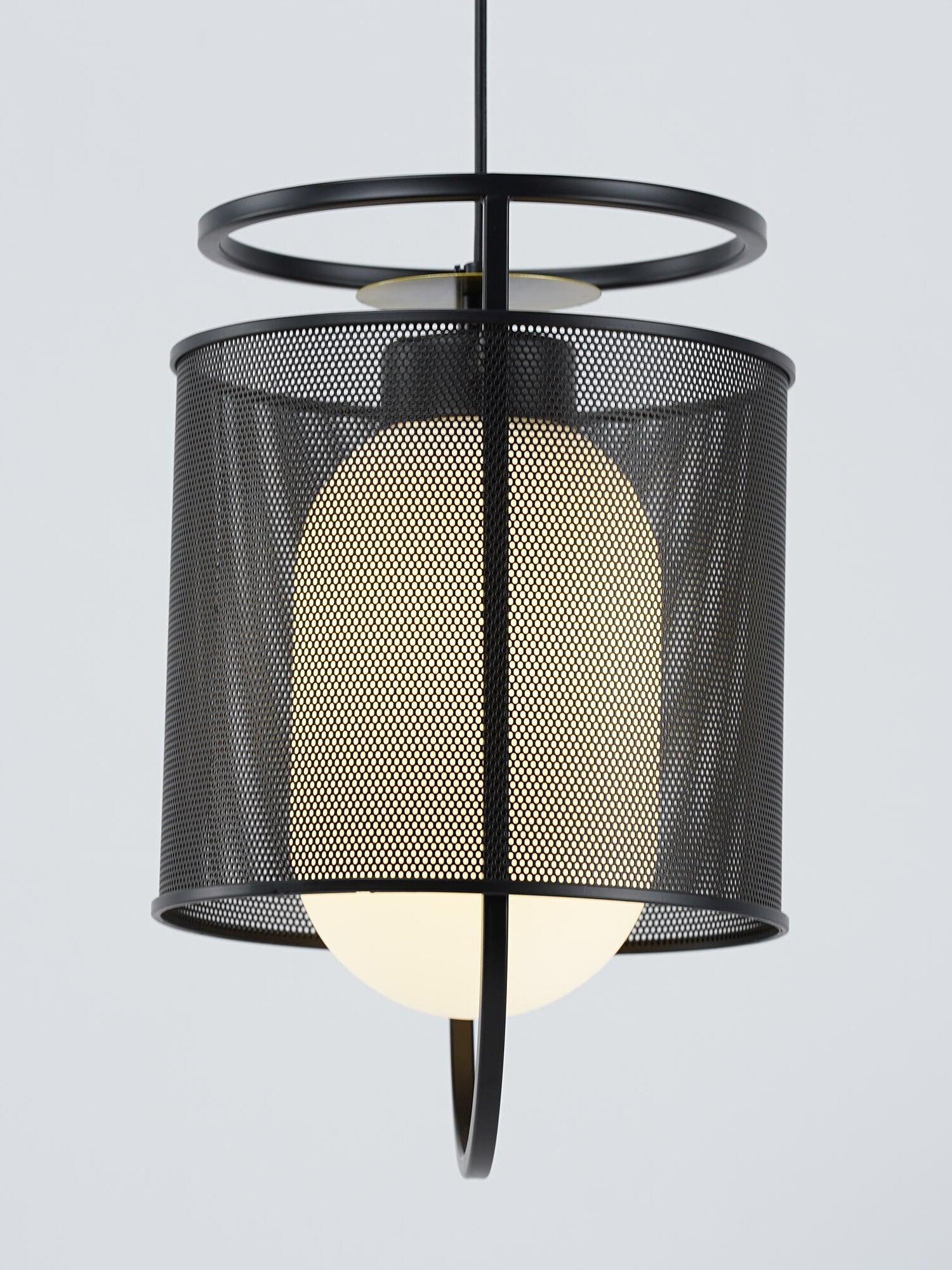 Black mesh pendant with bright lower bulb on pale background
