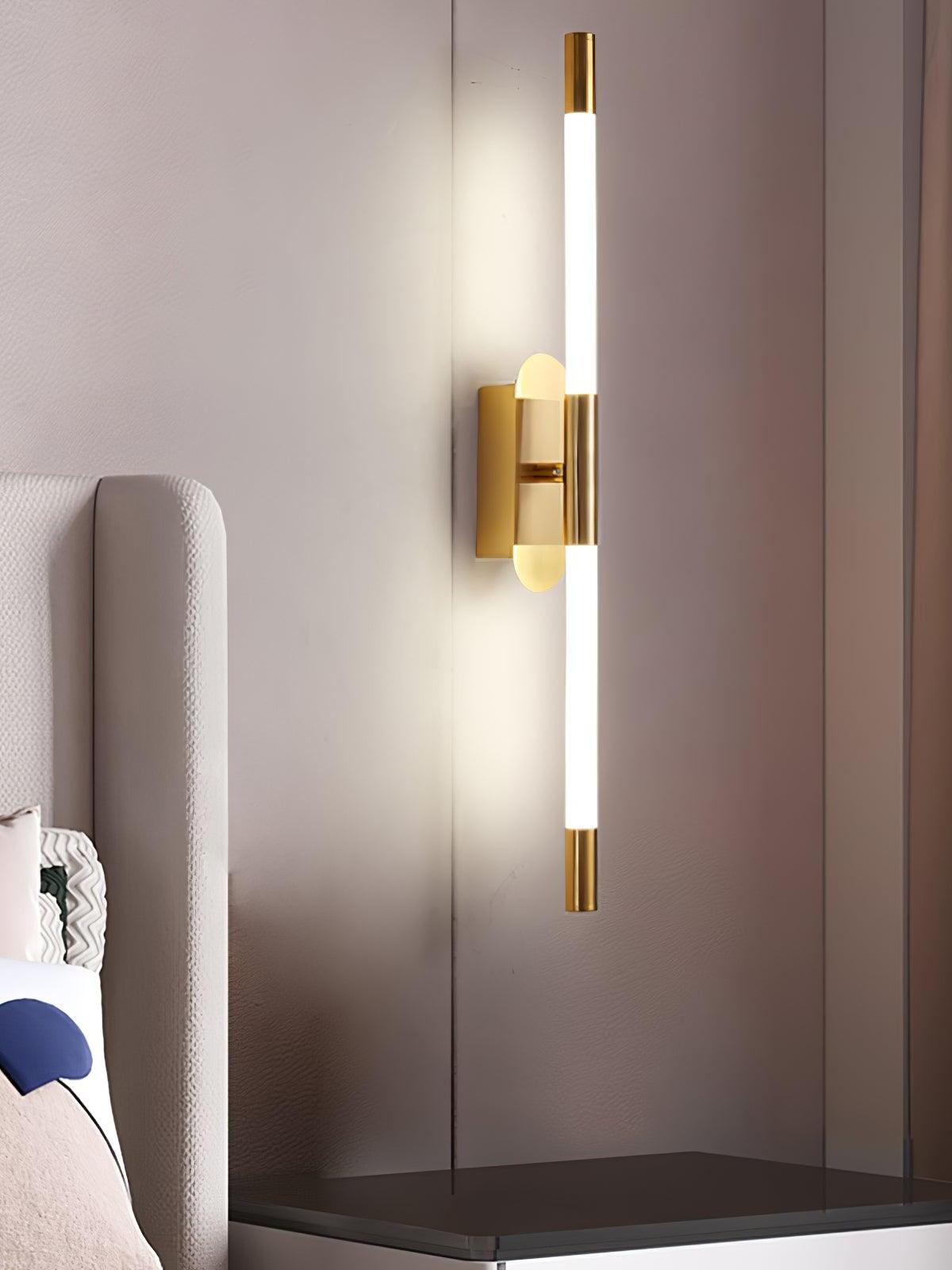 Gold-finish Agnes wall light above a bedside surface beside an upholstered headboard