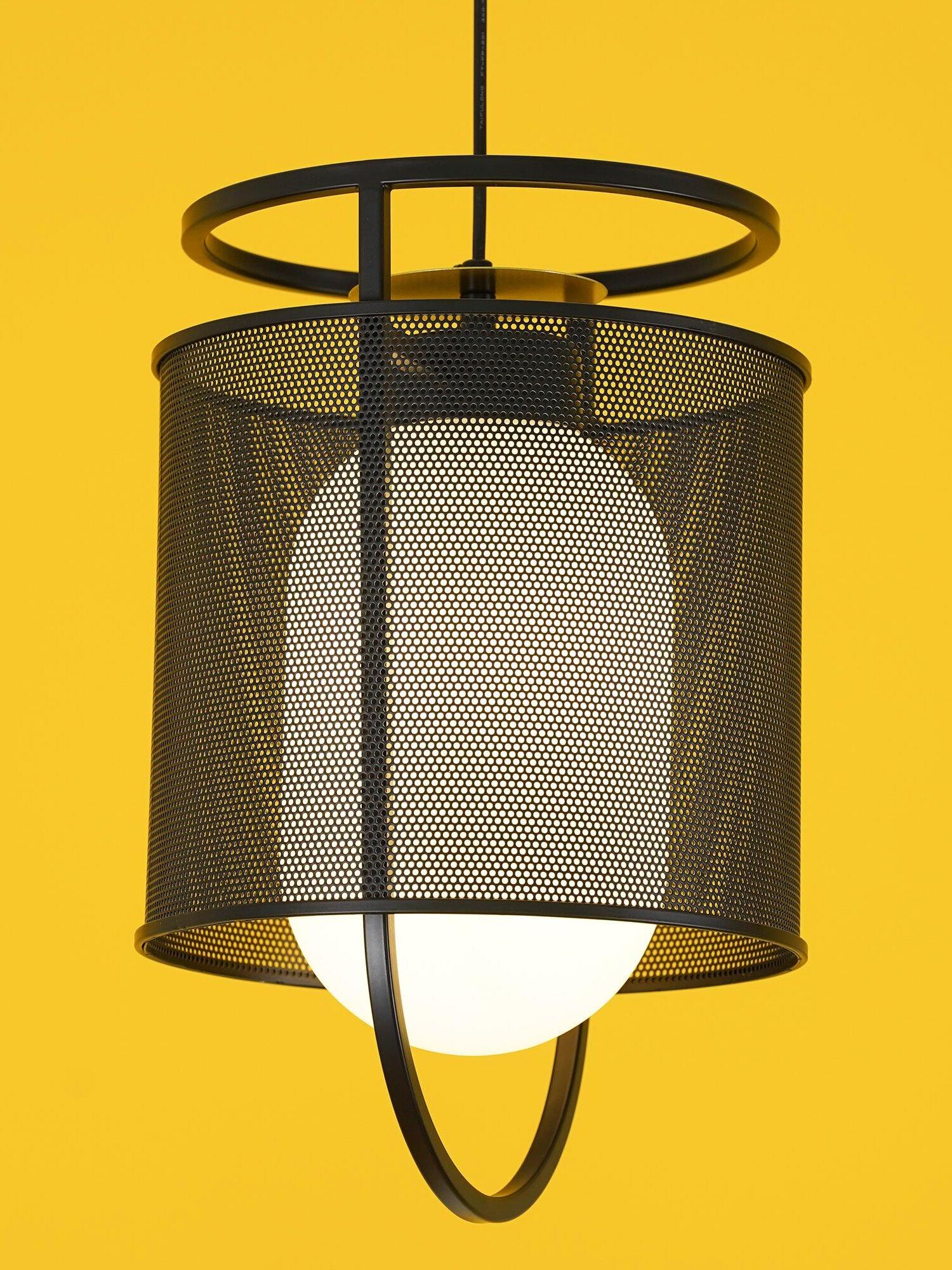 Close black mesh pendant with pale diffuser against yellow