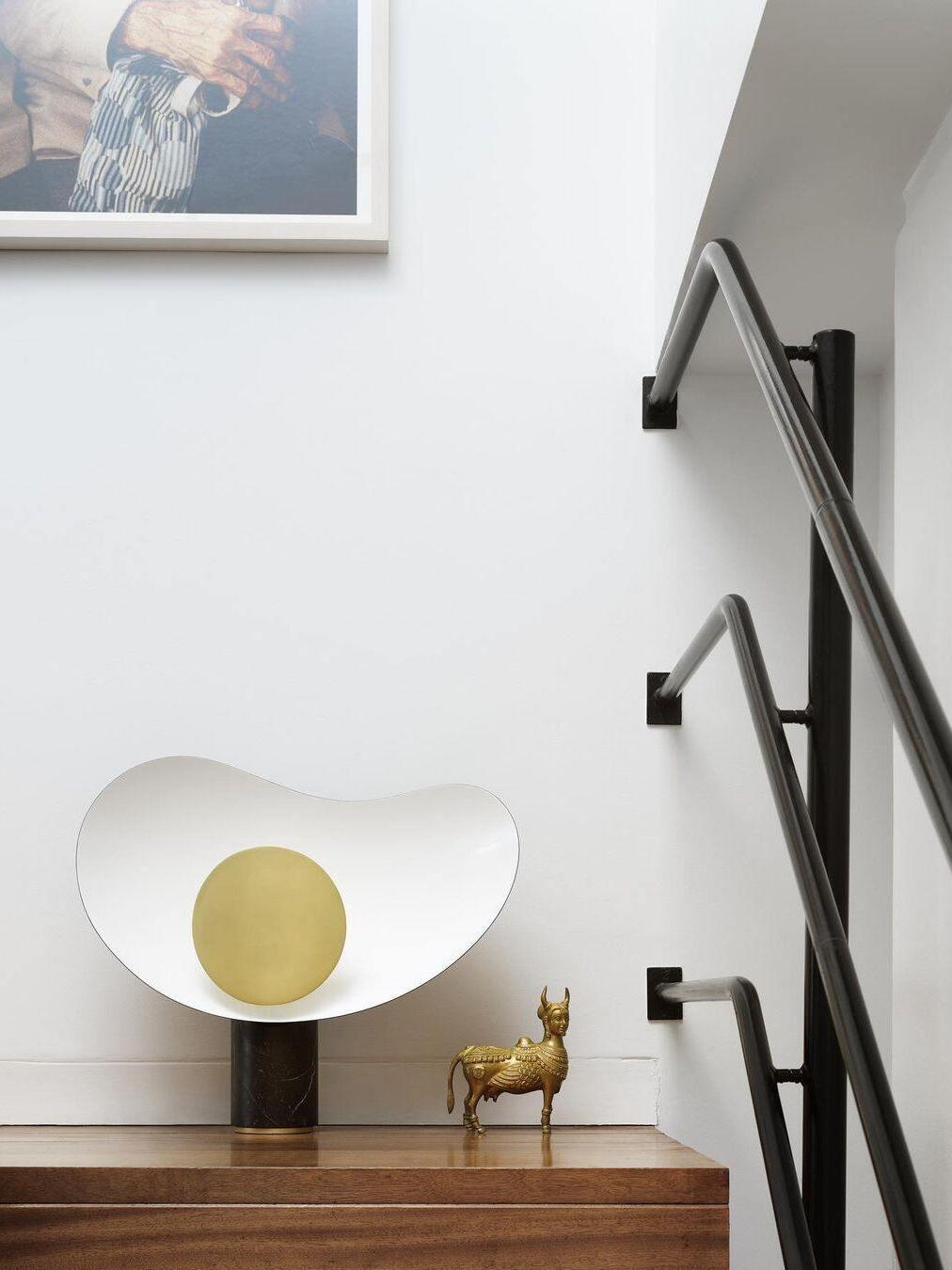 White curved-shade lamp and gold ornament by staircase