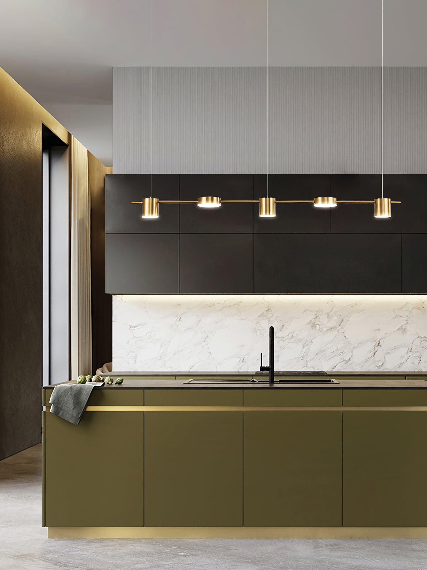 Gold linear pendant over a kitchen counter with green cabinetry
