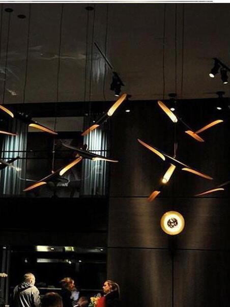 Black and gold pipe pendants hanging at different angles over restaurant seating